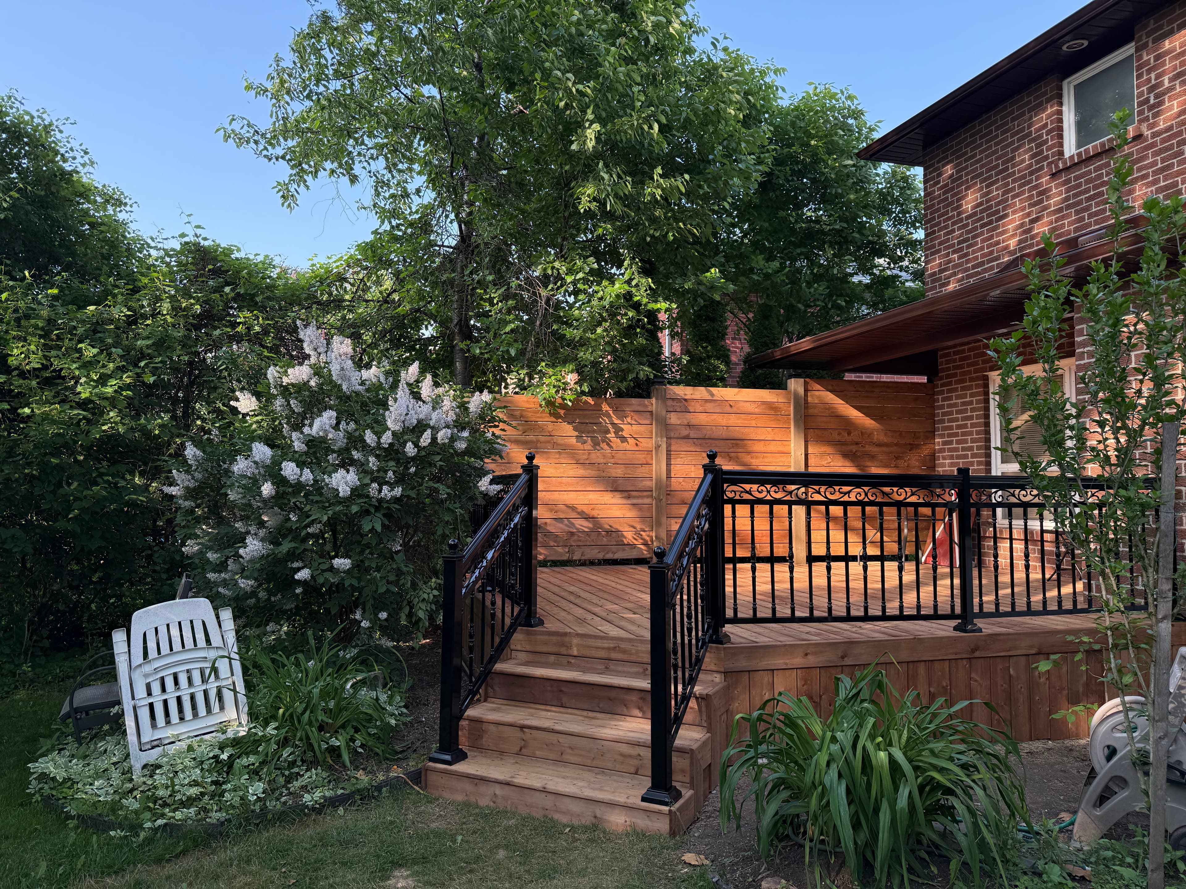 Front view of deck showing staircase with metal railings and backyard landscaping