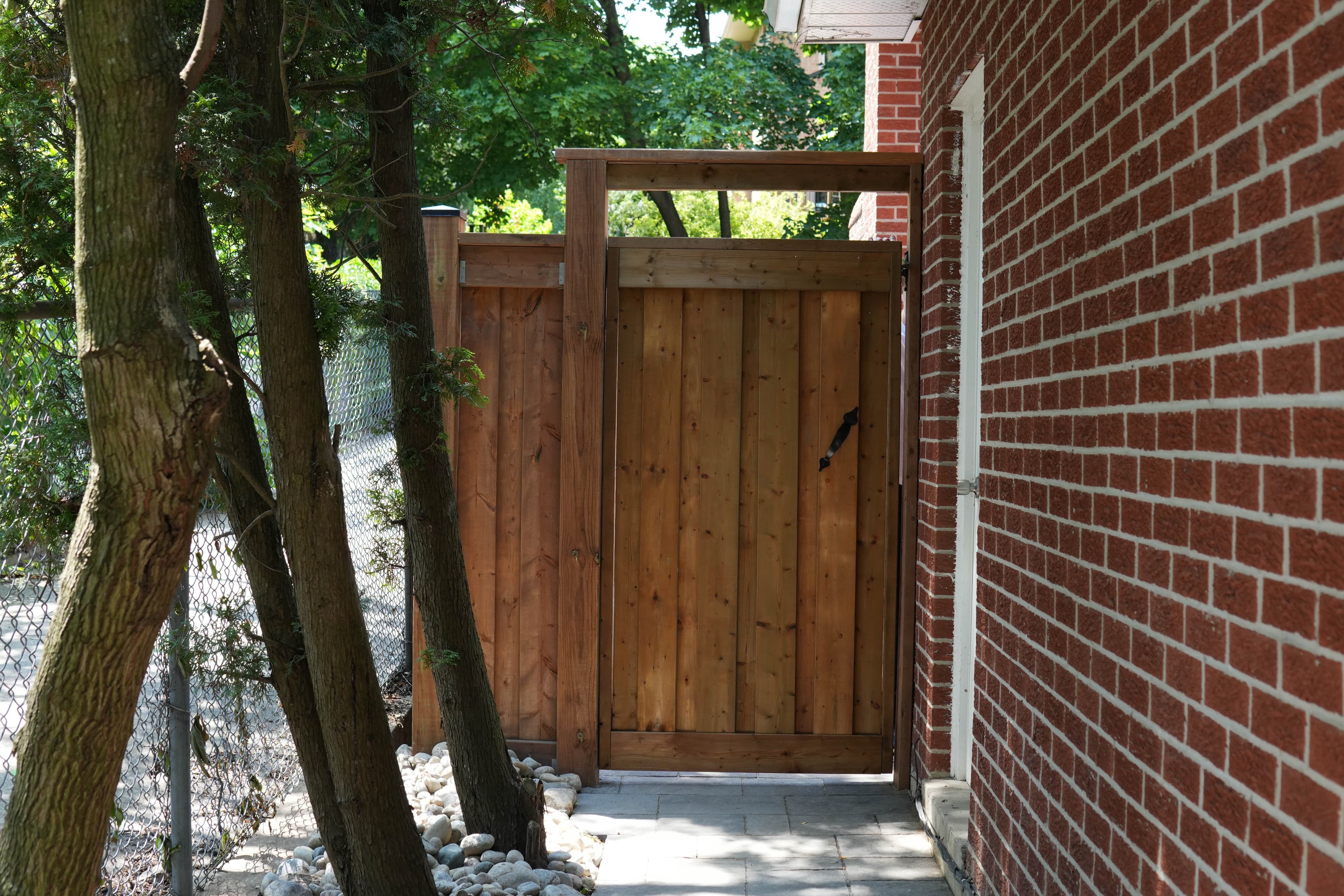 New wood privacy fence with a custom matching gate beside a brick house in Mississauga